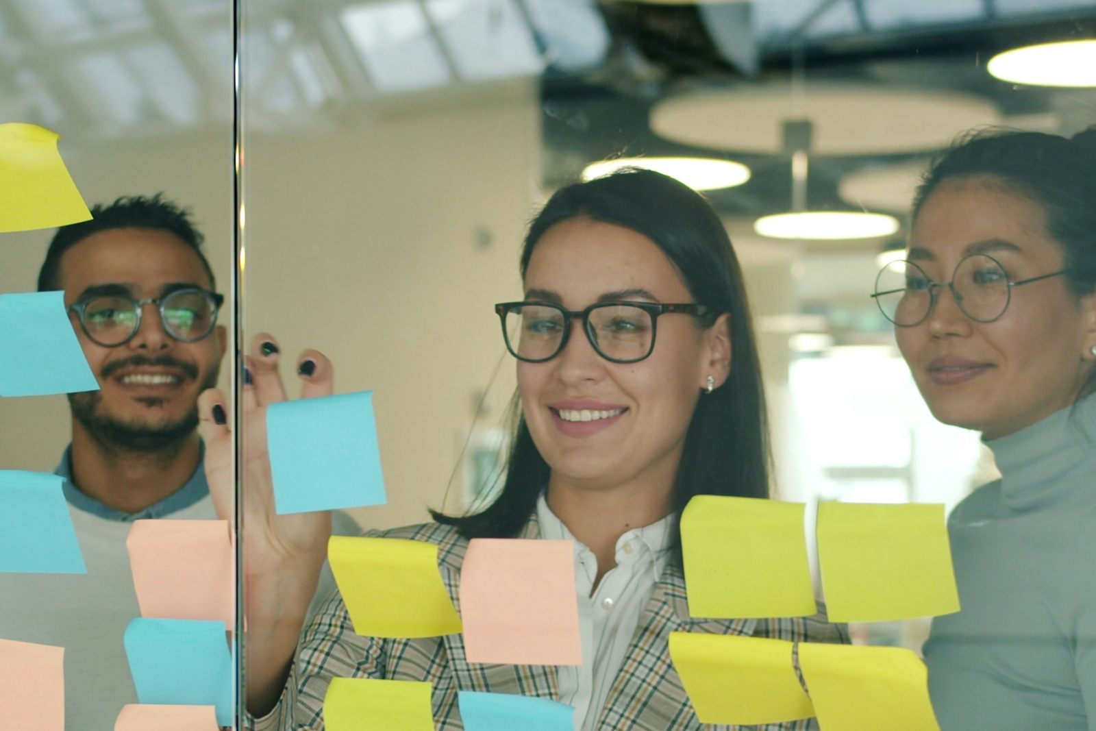 Colleagues planning with sticky notes on a glass wall